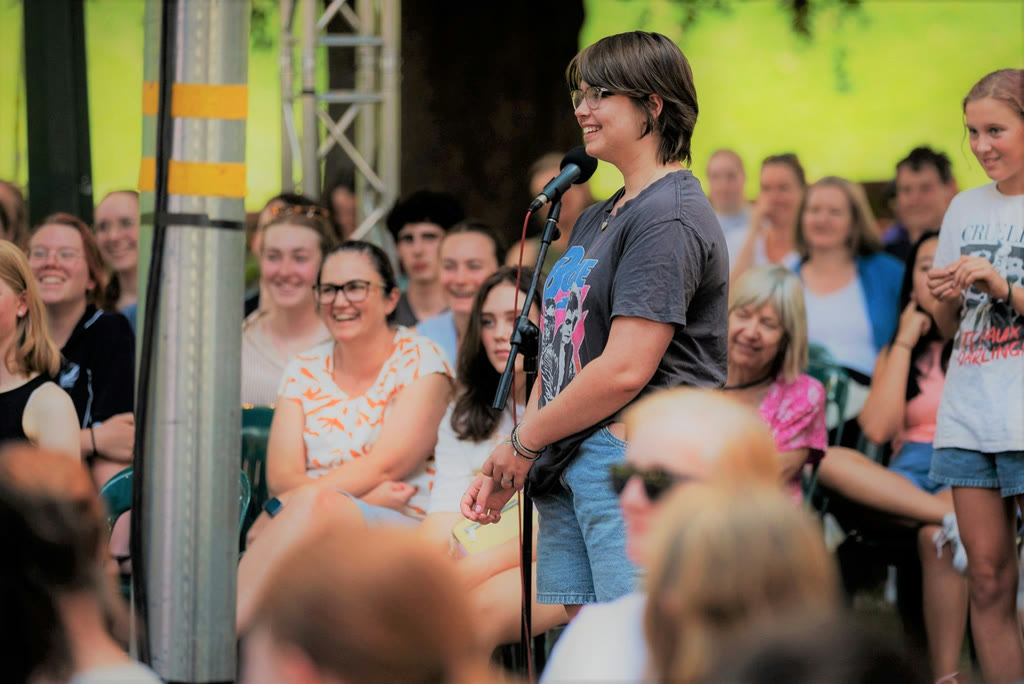 A young artist speaking into a microphone to a crowd