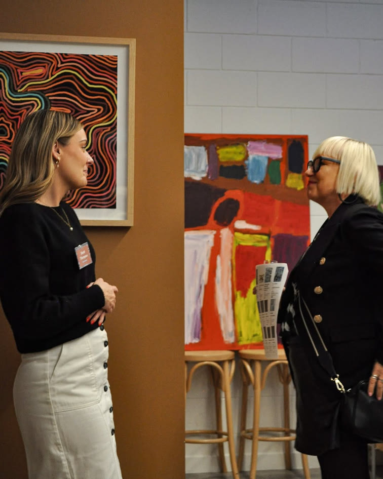 Two visitors talking in front of paintings