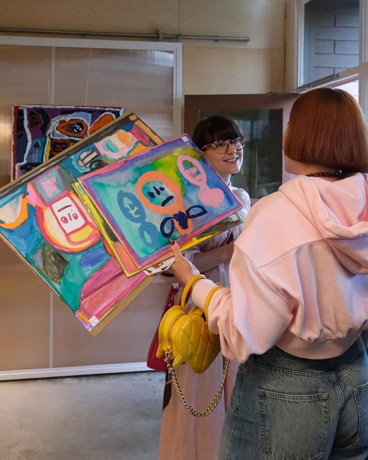 An artist holding up a colourful painted work