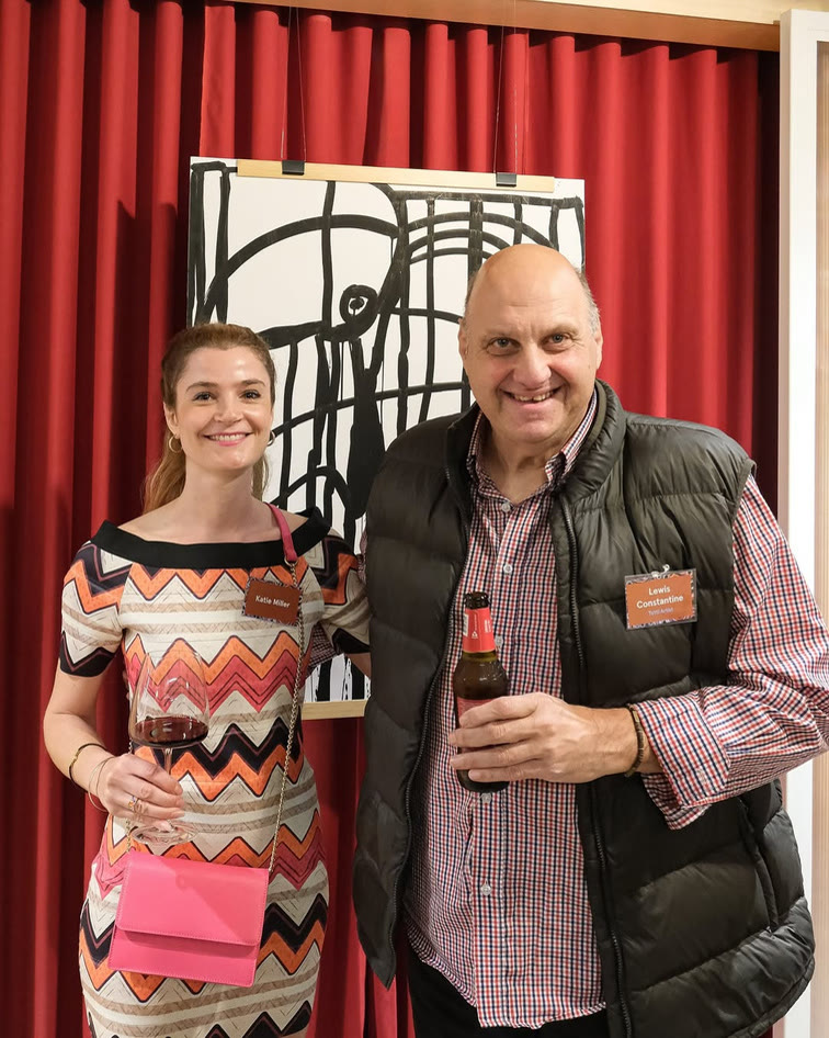 Two guests posing in front of a black and white artwork