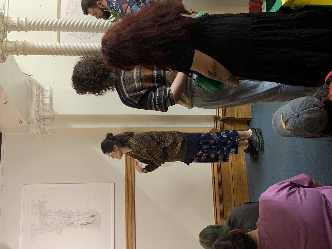 Lia giving a talk to a gathered audience in a gallery