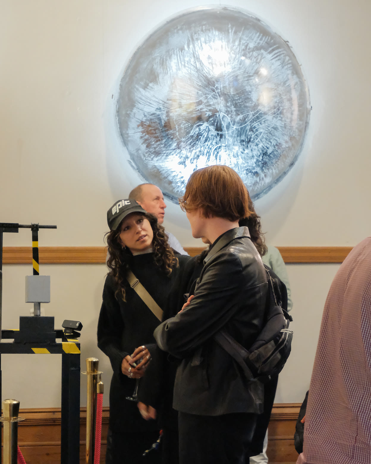 Visitors beneath a large silver circular work