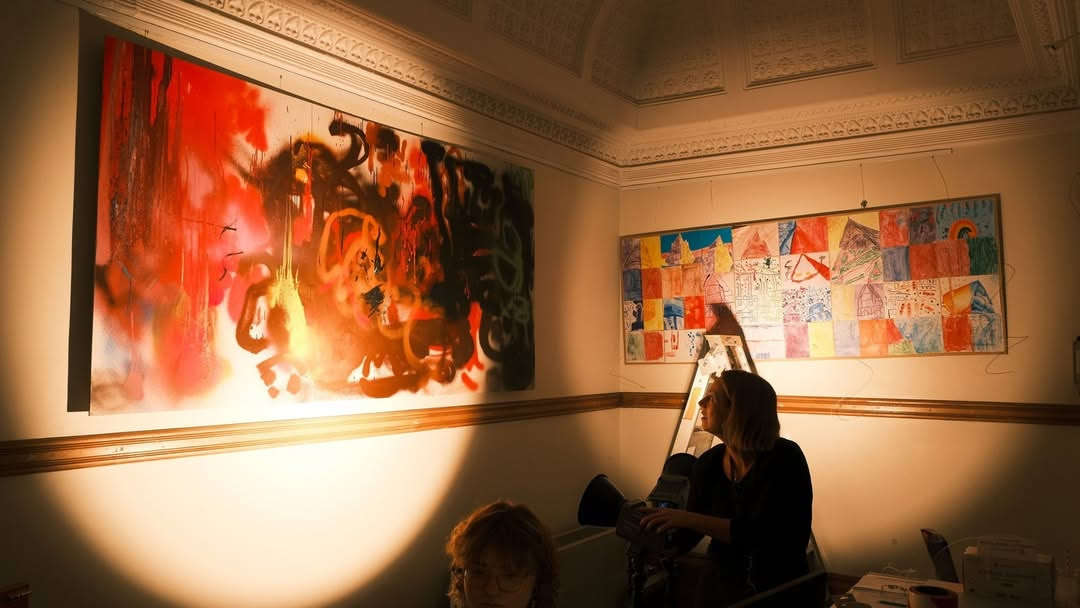Spotlit paintings in a darkened gallery room